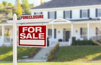 Foreclosue Sign on Top of For Sale Sign in Front of House